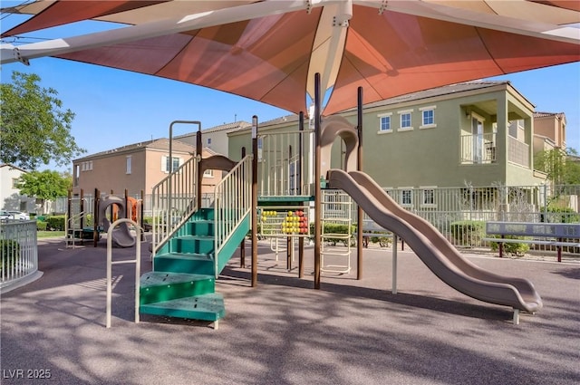 communal playground featuring fence and a residential view
