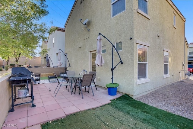 rear view of property with a patio, fence, and stucco siding