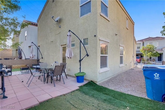rear view of house featuring a patio, fence, and stucco siding