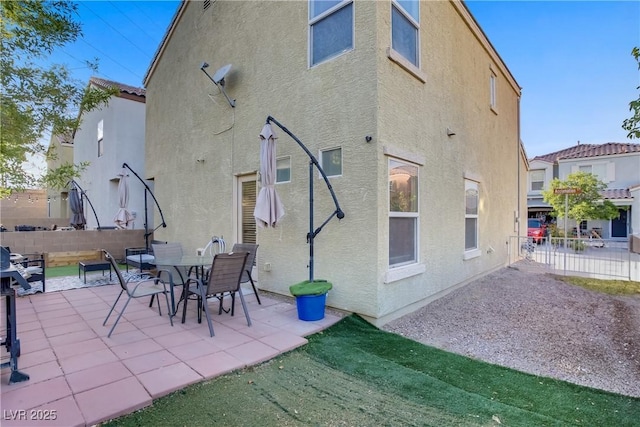 back of property featuring fence, stucco siding, and a patio area