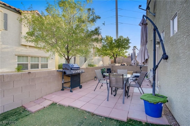 view of patio with fence, outdoor dining area, and a grill