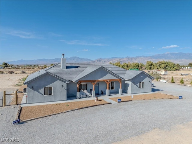 3880 Rudek St, Pahrump, NV 89061 - view of front of house featuring a mountain view, a chimney, stucco siding, and a porch