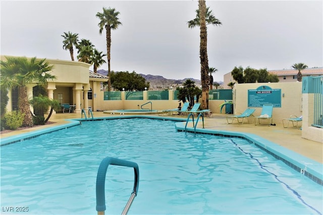 pool featuring a mountain view, fence, and a patio area