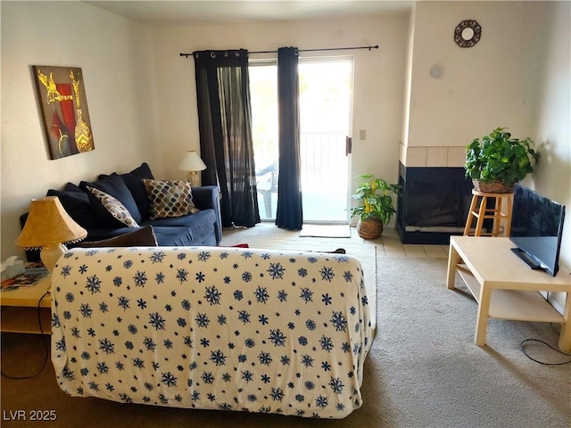 living area with a tile fireplace and carpet