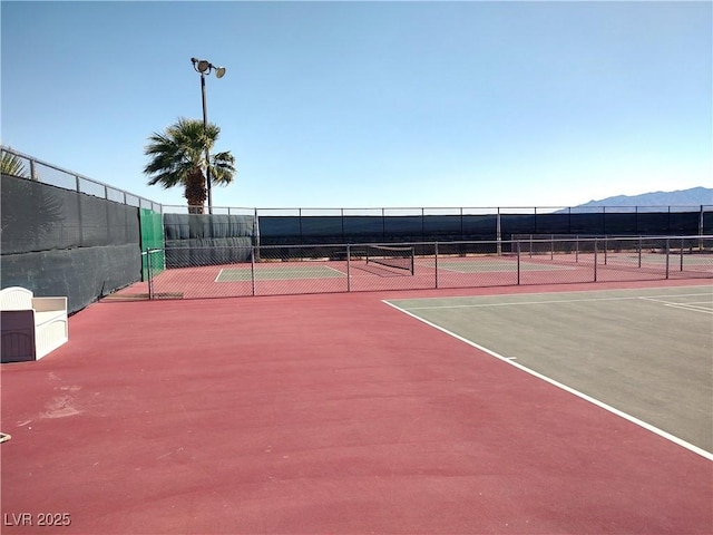 view of sport court with a mountain view and fence