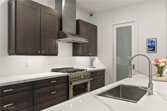 kitchen featuring high end stainless steel range, wall chimney exhaust hood, a sink, dark brown cabinetry, and light stone countertops