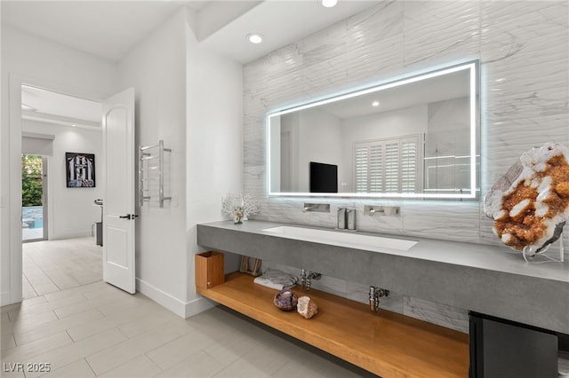 bathroom with baseboards, vanity, and recessed lighting