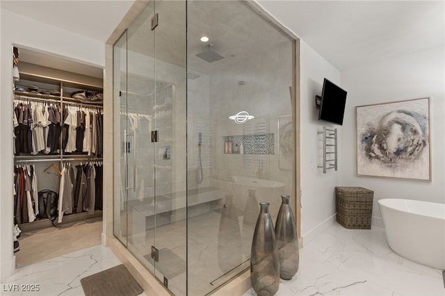 bathroom with a shower stall, a walk in closet, a freestanding tub, marble finish floor, and baseboards