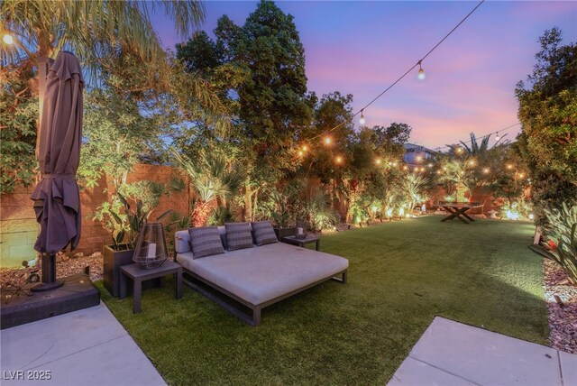 yard at dusk featuring fence, an outdoor living space, and a patio area