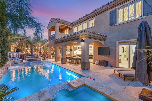 rear view of property with a patio, an outdoor hangout area, a tiled roof, a balcony, and an in ground hot tub
