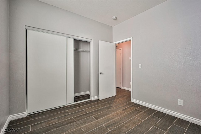 unfurnished bedroom featuring baseboards, wood tiled floor, and a closet