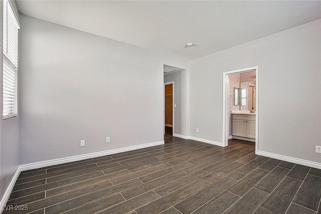 empty room featuring baseboards, dark wood-style floors, and a wealth of natural light
