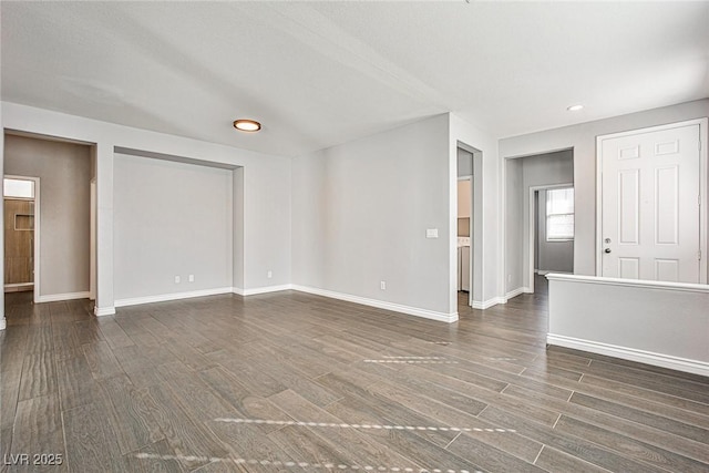 unfurnished living room with baseboards, recessed lighting, and dark wood finished floors