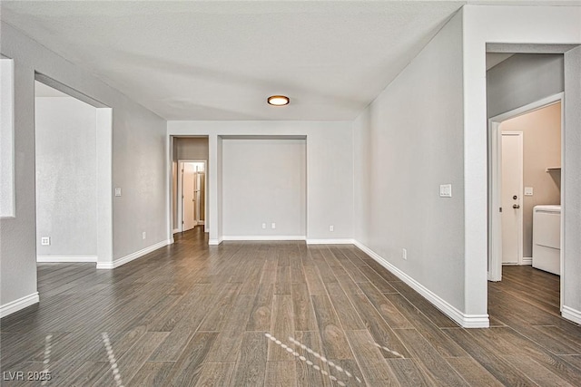 spare room with baseboards, washer / clothes dryer, and wood finished floors