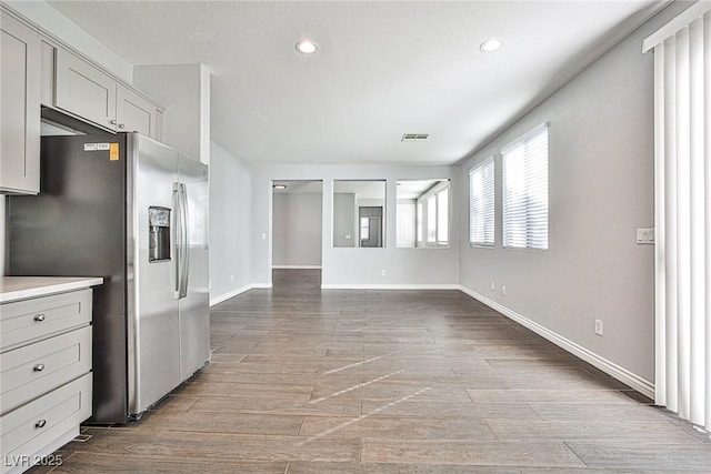 kitchen with wood finished floors, baseboards, stainless steel refrigerator with ice dispenser, visible vents, and recessed lighting