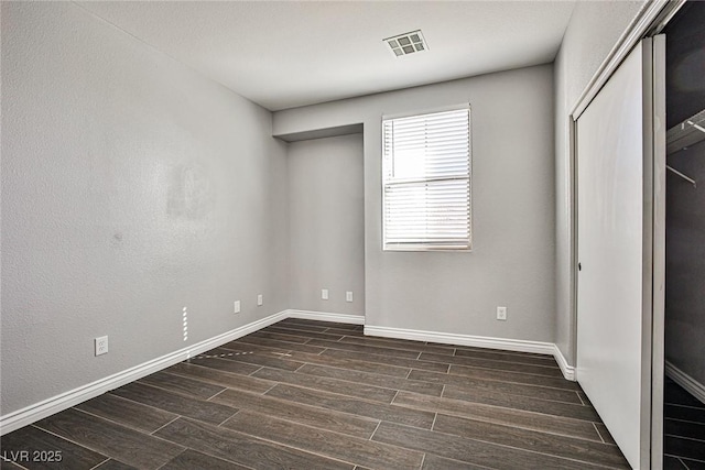 unfurnished bedroom featuring dark wood-style floors, baseboards, and visible vents