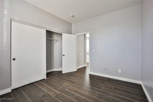 unfurnished bedroom with baseboards, wood finished floors, and a closet
