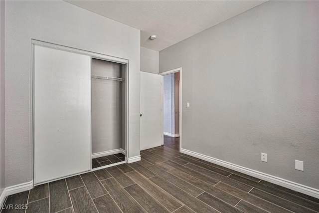 unfurnished bedroom with wood tiled floor, a closet, and baseboards