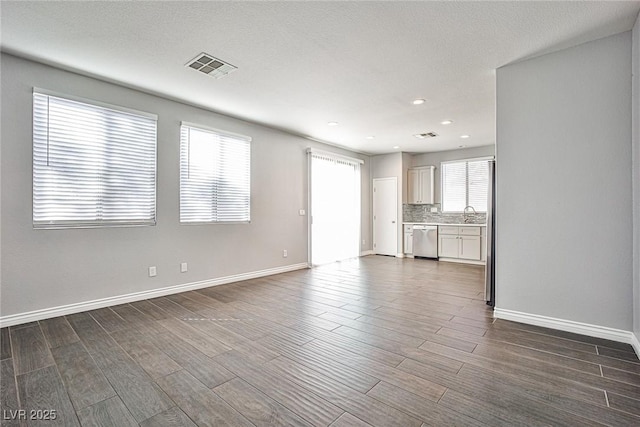 unfurnished living room with recessed lighting, dark wood finished floors, visible vents, a sink, and baseboards