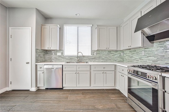 kitchen featuring stainless steel appliances, a sink, decorative backsplash, light countertops, and under cabinet range hood