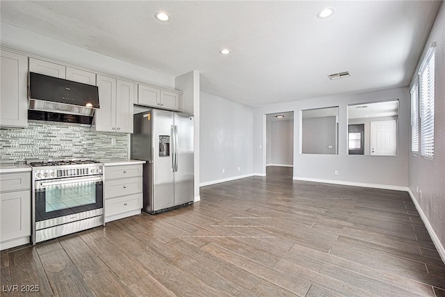 kitchen with decorative backsplash, appliances with stainless steel finishes, range hood, and light countertops