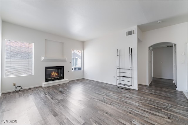 1838 N Jones Blvd, Las Vegas, NV 89108 - unfurnished living room with arched walkways, wood finished floors, a glass covered fireplace, and baseboards