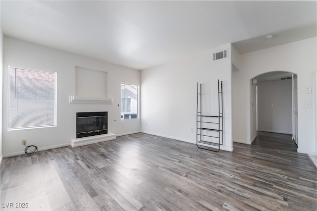 1838 N Jones Blvd, Las Vegas, NV 89108 - unfurnished living room featuring arched walkways, wood finished floors, a glass covered fireplace, and baseboards