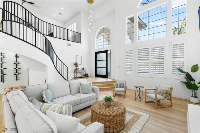 living area with wood finished floors, a towering ceiling, baseboards, and stairway