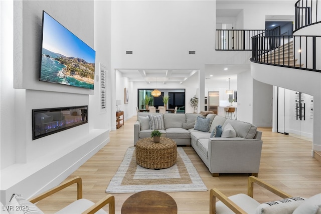 living area featuring visible vents, a high ceiling, and light wood-style floors