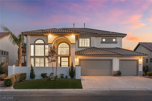 mediterranean / spanish home featuring stucco siding, an attached garage, driveway, and a tile roof