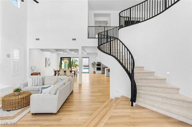living area featuring visible vents, wood finished floors, a high ceiling, and stairs