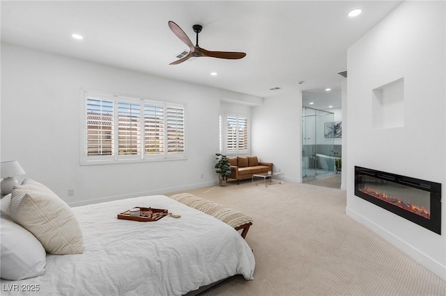carpeted bedroom featuring ensuite bathroom, visible vents, baseboards, a glass covered fireplace, and recessed lighting