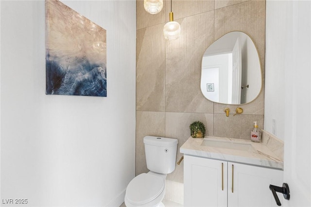 bathroom with tile walls, vanity, and toilet