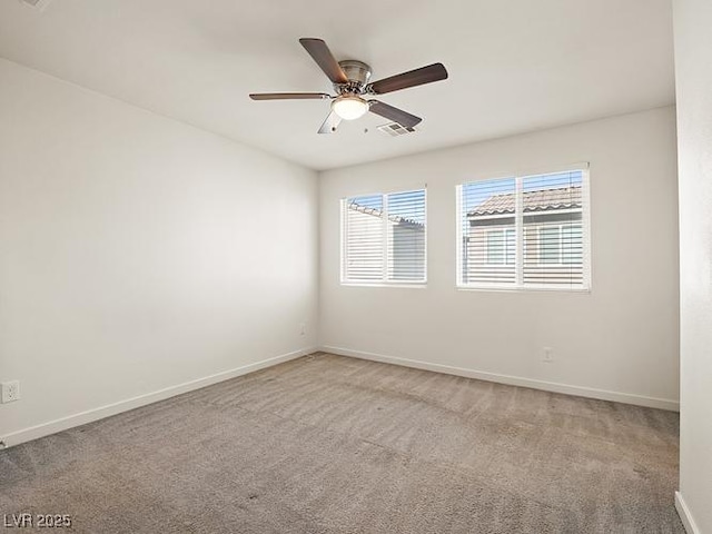 empty room with a ceiling fan, visible vents, light colored carpet, and baseboards