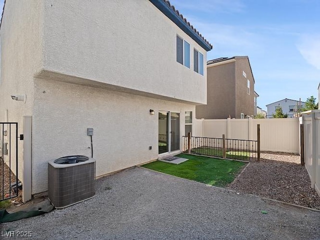 back of house featuring stucco siding, central AC, a patio area, and a fenced backyard