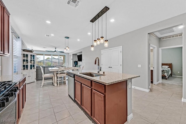 kitchen with stainless steel dishwasher, a sink, range, light stone countertops, and visible vents