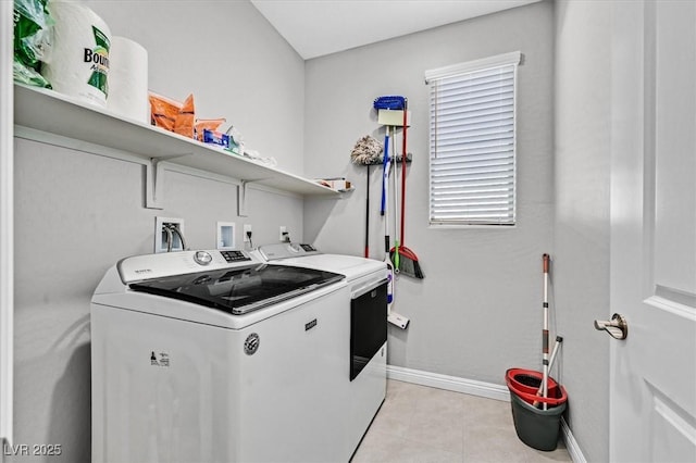 clothes washing area with light tile patterned floors, washing machine and clothes dryer, baseboards, and laundry area