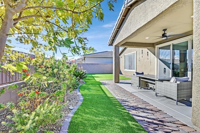 view of yard with a fenced backyard, a ceiling fan, and a patio
