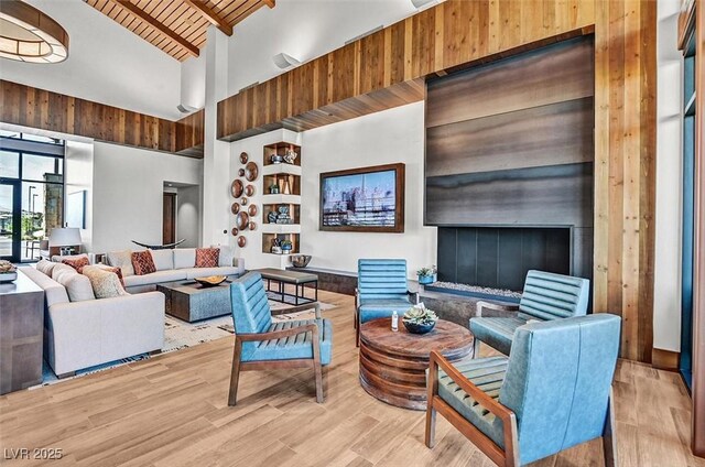 living area featuring wood finished floors, beam ceiling, high vaulted ceiling, and wood ceiling