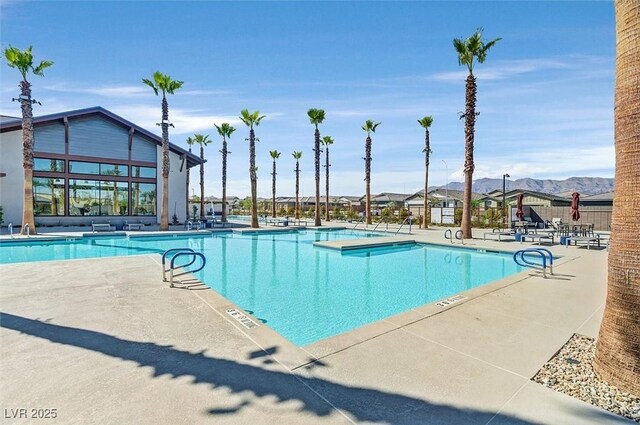 community pool with fence, a patio area, and a mountain view