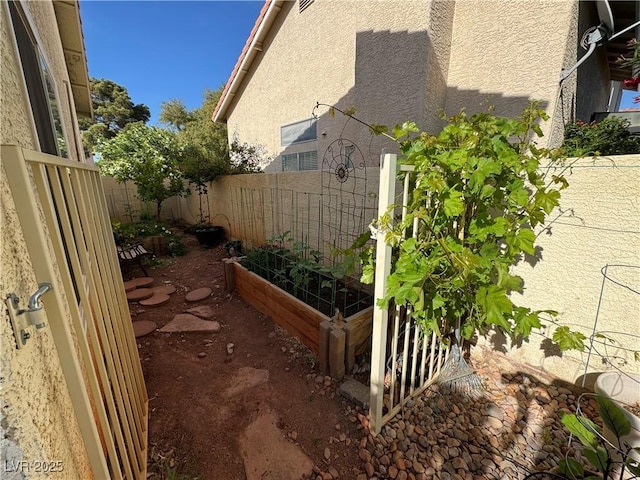 2807 Camelback Ln, Henderson, NV 89074 - view of side of property with fence, stucco siding, and a garden