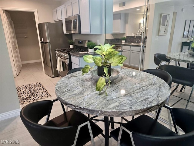 kitchen featuring stainless steel appliances, baseboards, a sink, and dark countertops
