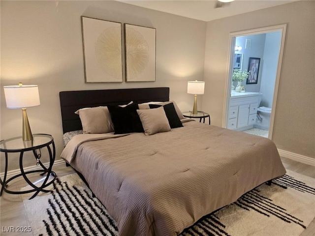 bedroom with ensuite bath, baseboards, and light wood-style floors