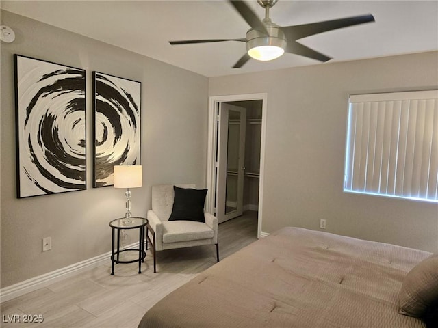 bedroom featuring a walk in closet, ceiling fan, and baseboards