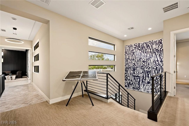 hallway featuring carpet, visible vents, baseboards, and an upstairs landing