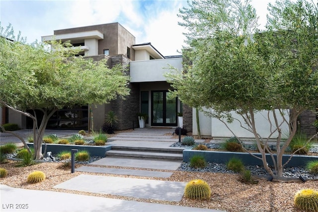 view of front of property featuring stucco siding, a balcony, and french doors