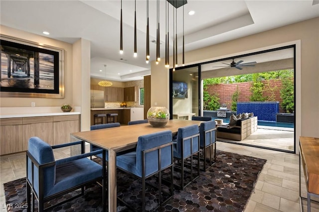 dining space with recessed lighting, a raised ceiling, stone finish flooring, and a ceiling fan