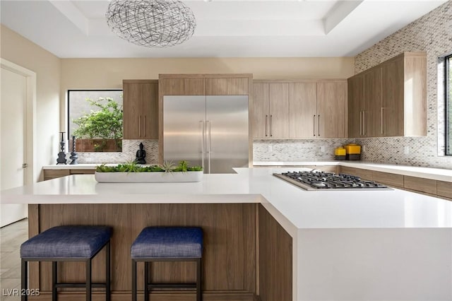 kitchen with backsplash, stainless steel appliances, light countertops, and a raised ceiling