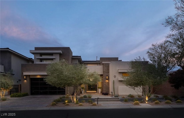 contemporary home with stucco siding, aphalt driveway, and a garage