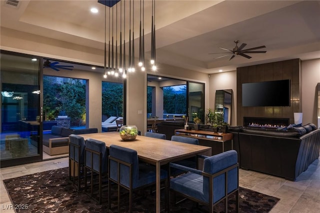 dining area featuring a tray ceiling, visible vents, recessed lighting, ceiling fan, and a tile fireplace